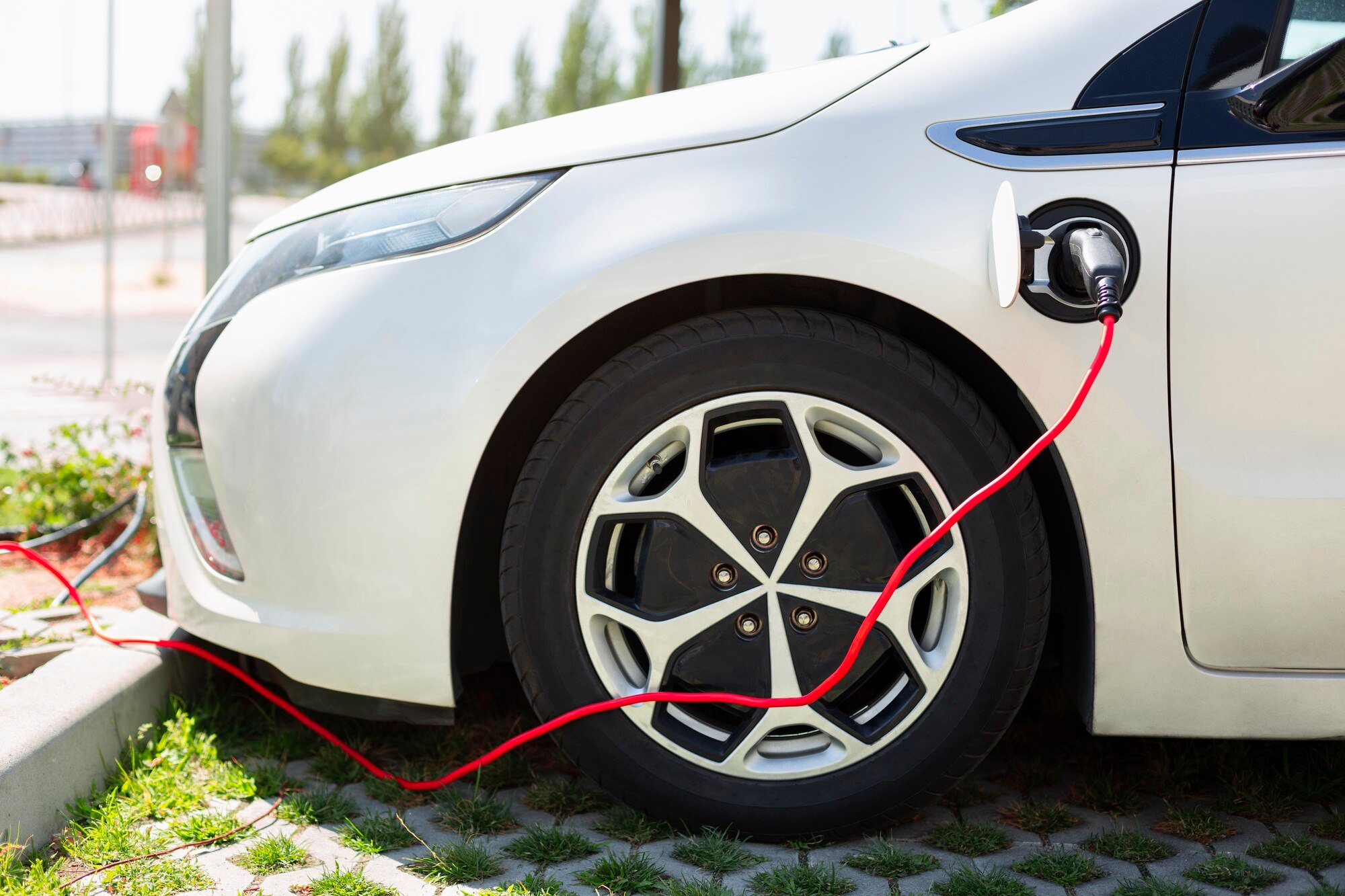 Sähköauto latauksessa kotipihalla ja renkaat näkyvissä